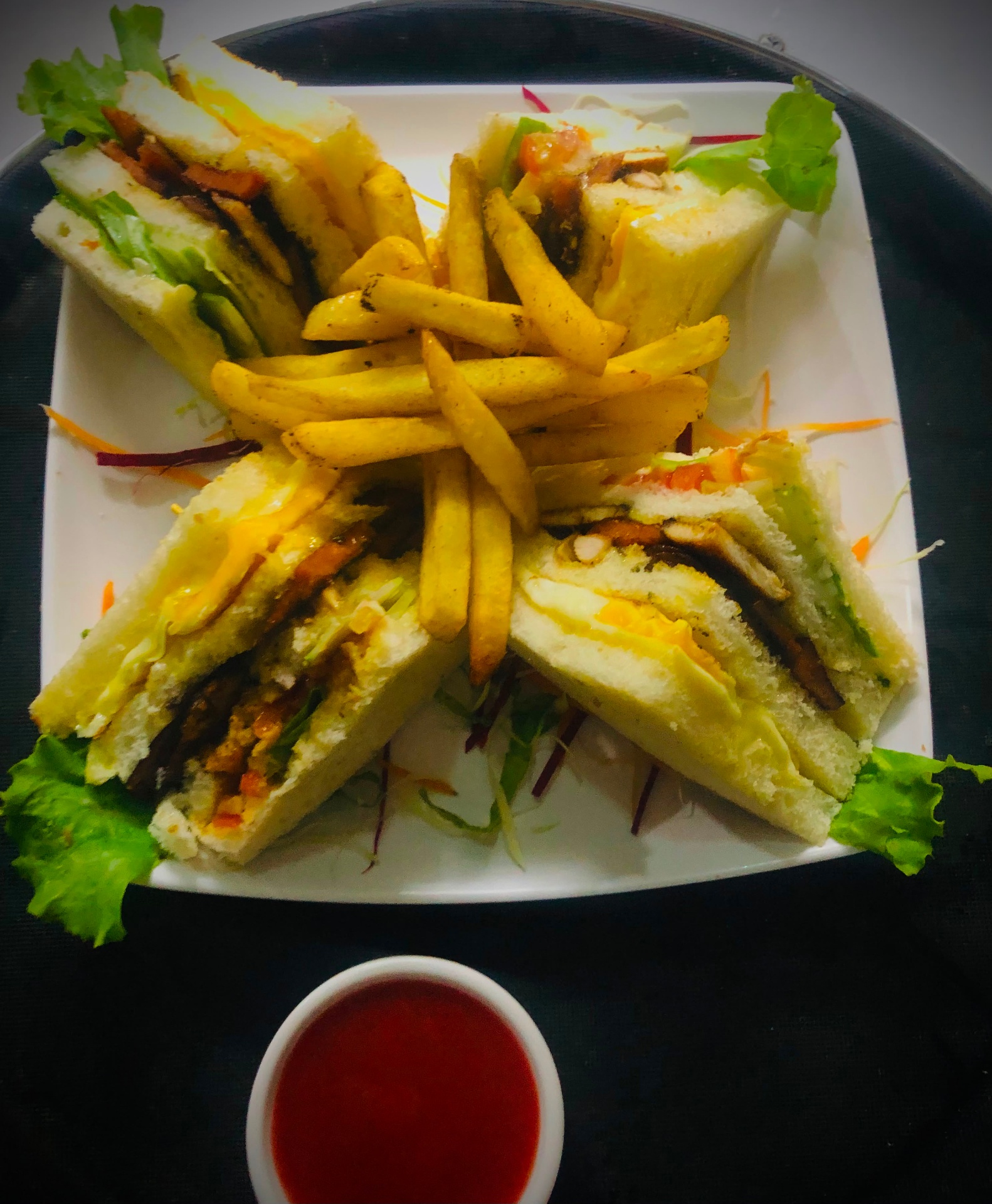 Club sandwich quarters arranged around french fries with ketchup on the side